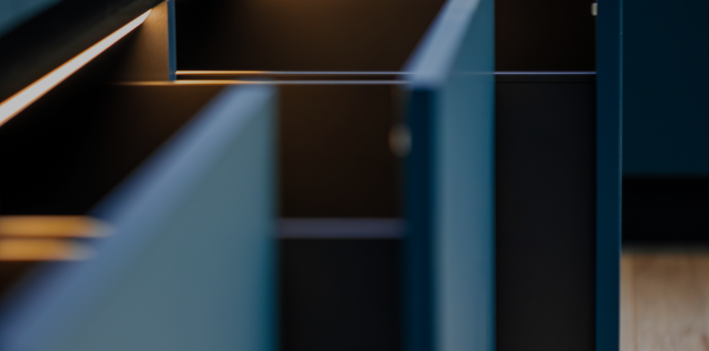 Close-up of open dark blue modern cabinetry featuring warm LED strip lighting inside.
