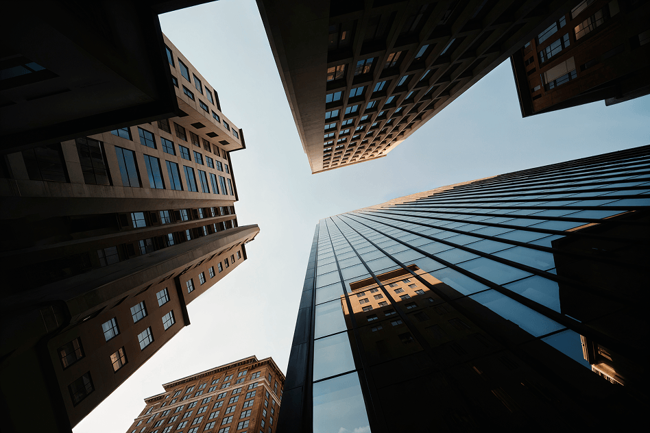 Low-angle view looking directly up at tall skyscrapers framing a square patch of clear sky.