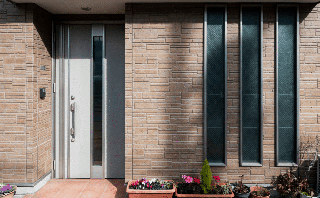 An outside image of a modern brick house with vertical windows and a white door.