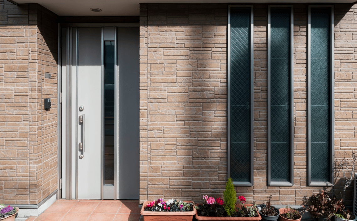 An outside image of a modern brick house with vertical windows and a white door.