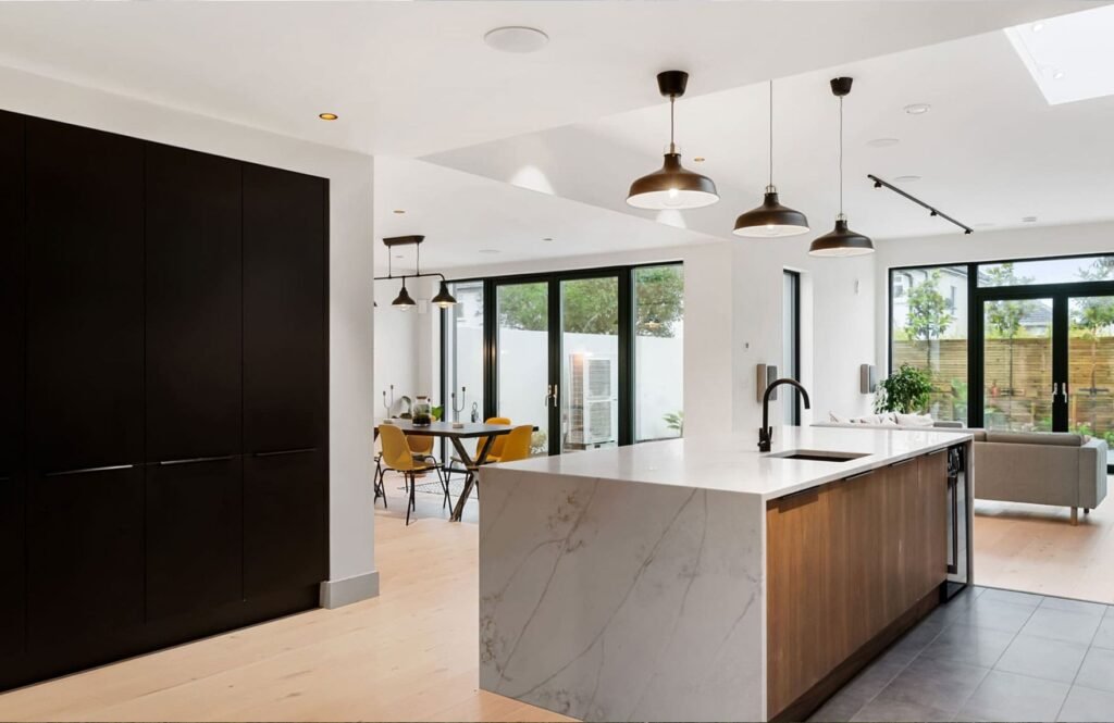 A modern black & marble kitchen with living area.