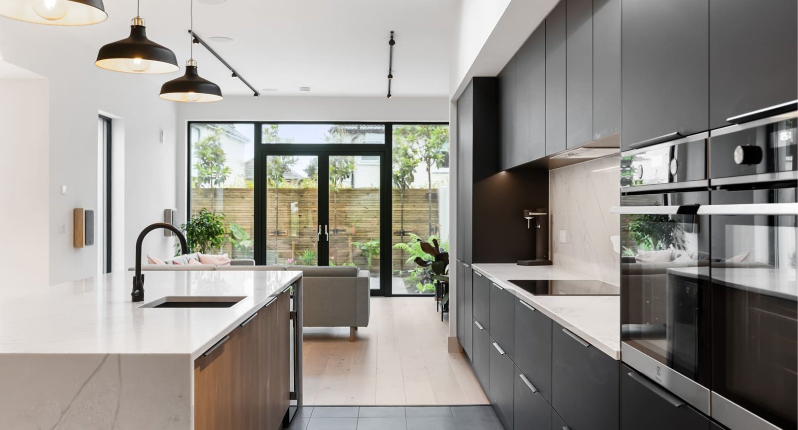 A modern black & marble kitchen with living area.