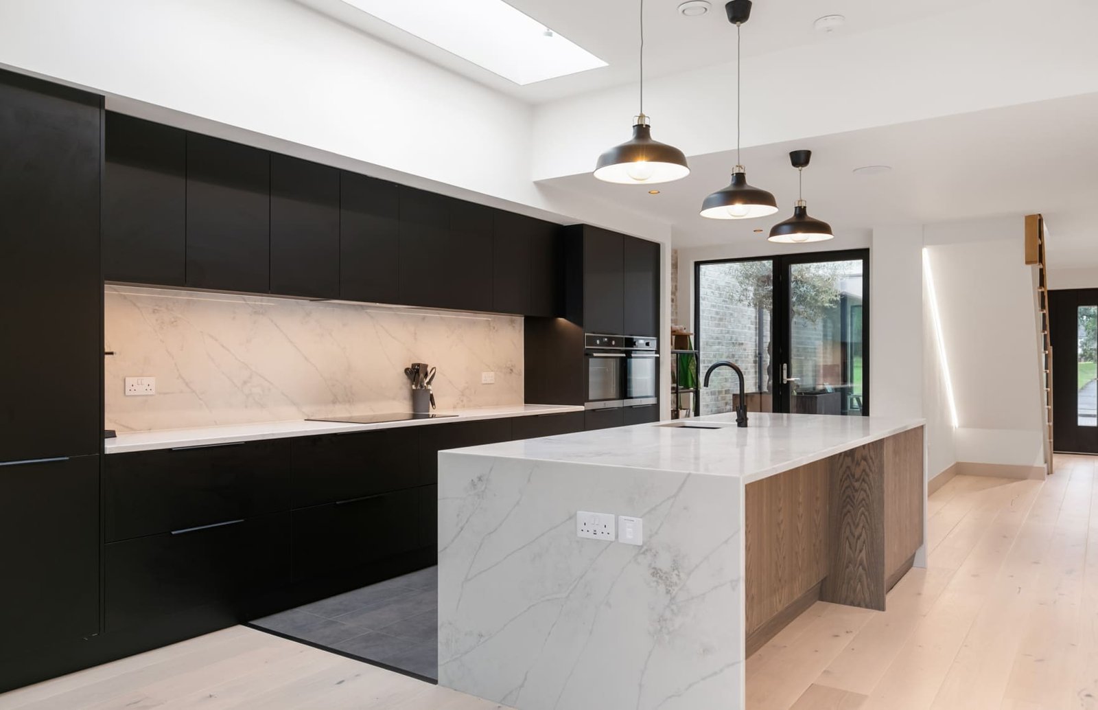 A modern black & marble kitchen with living area.
