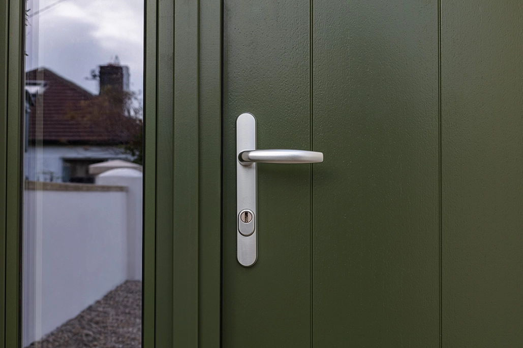 Close up of an olive green door with a silver handle.