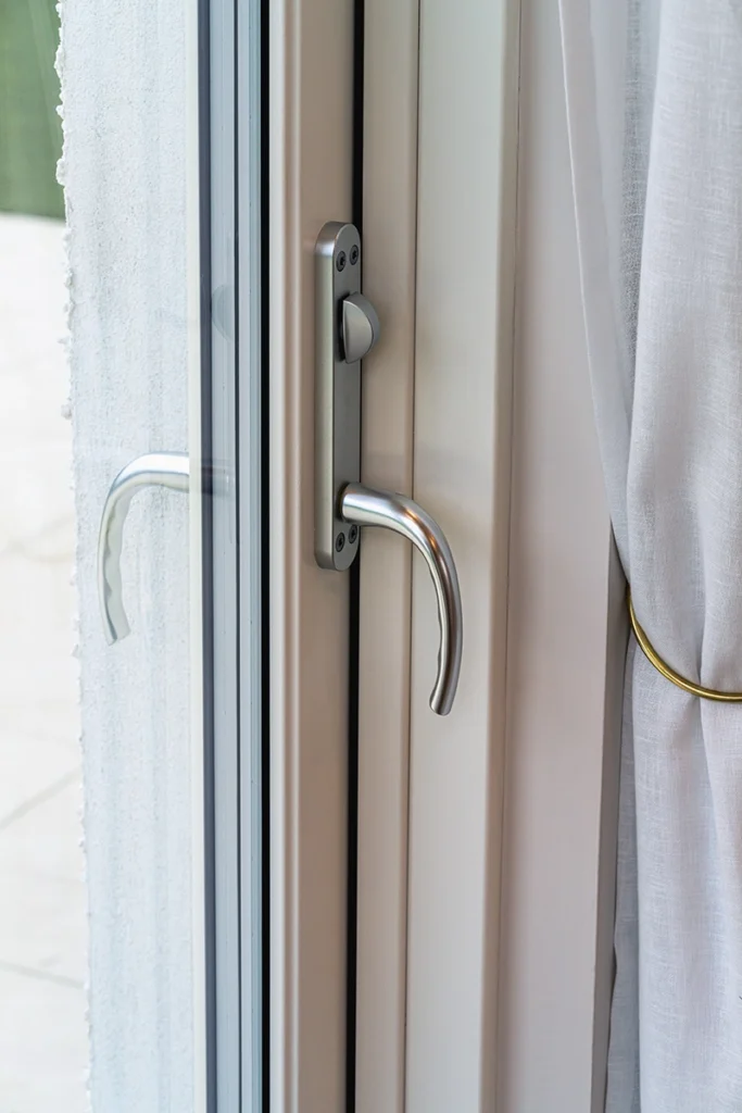Close-up of a window handle on a cream frame.