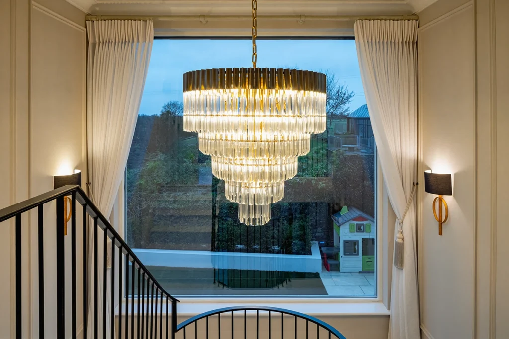 A chandelier hanging next to a modern staircase.