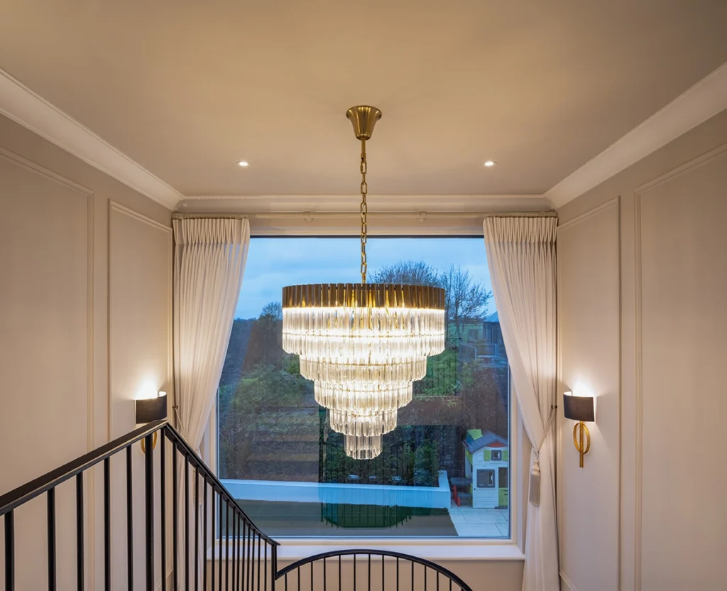 A chandelier hanging next to a modern staircase.