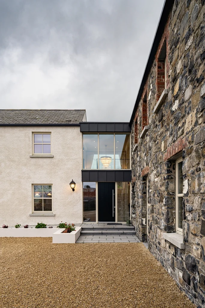Glass link entrance connecting traditional white rendered and stone buildings.