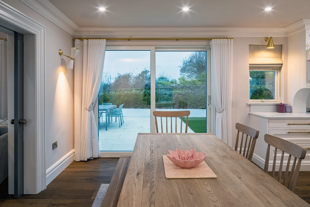A modern white kitchen with a white curtain with a golden railing.