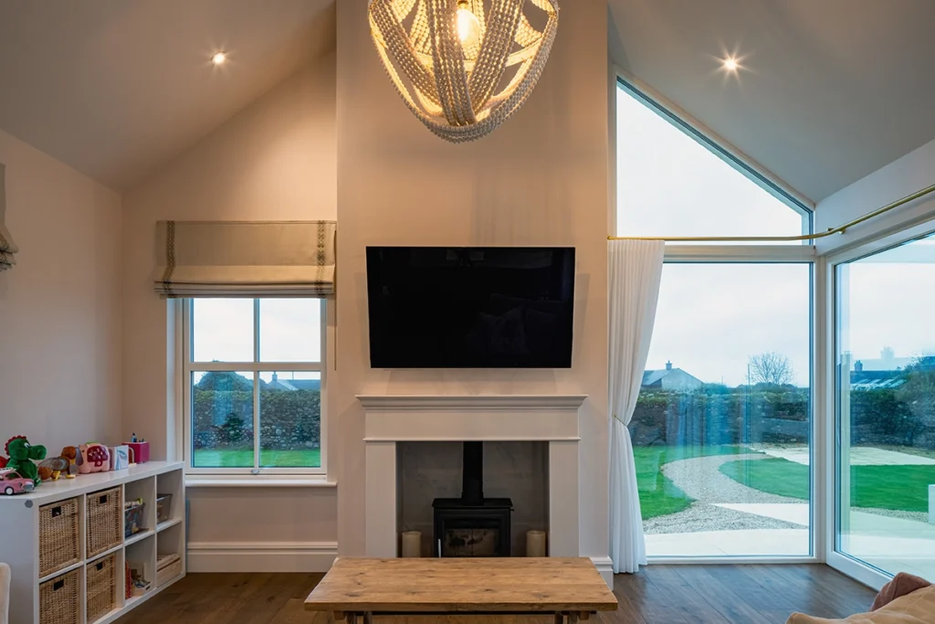 Bright living area featuring vaulted ceilings, a fireplace, and large floor-to-ceiling windows.