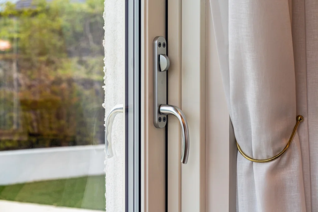Close-up of a window handle on a cream frame.
