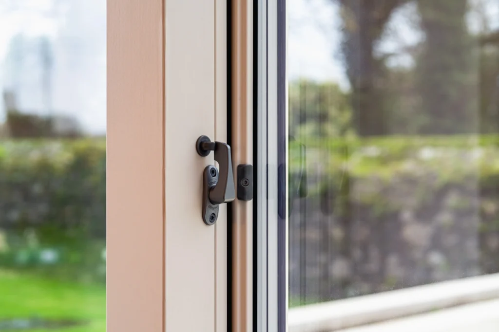 Close-up of a window latch handle on a cream frame.