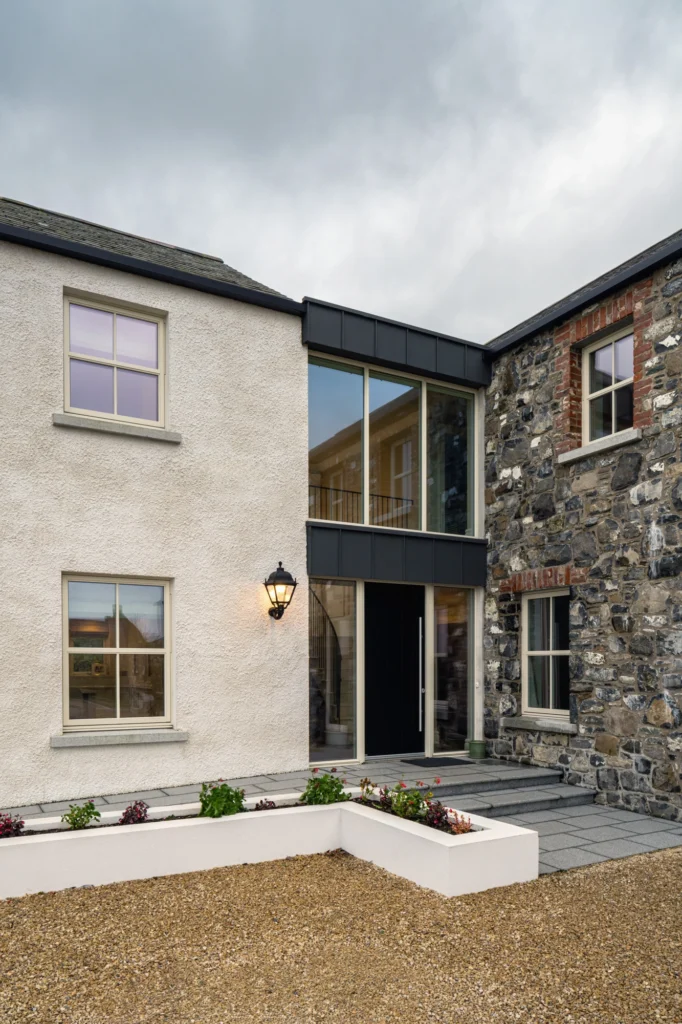Glass link entrance connecting traditional white rendered and stone buildings.