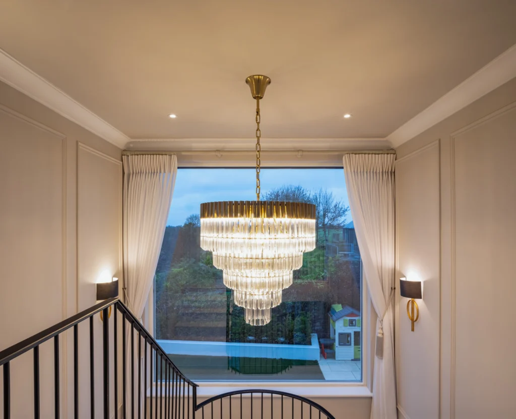 A chandelier hanging next to a modern staircase.
