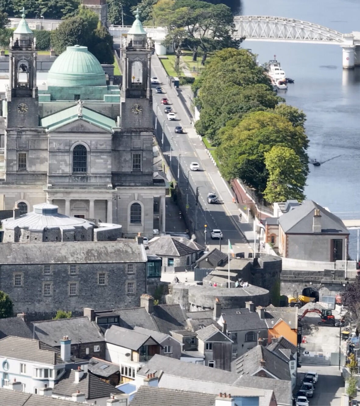An aerial view of a large church with a green dome next to a river.