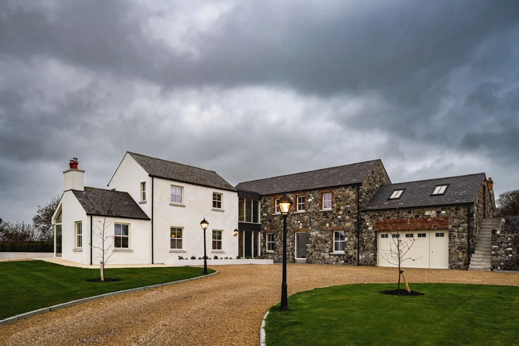 Country estate with white render and stone buildings connected by a modern glass link.